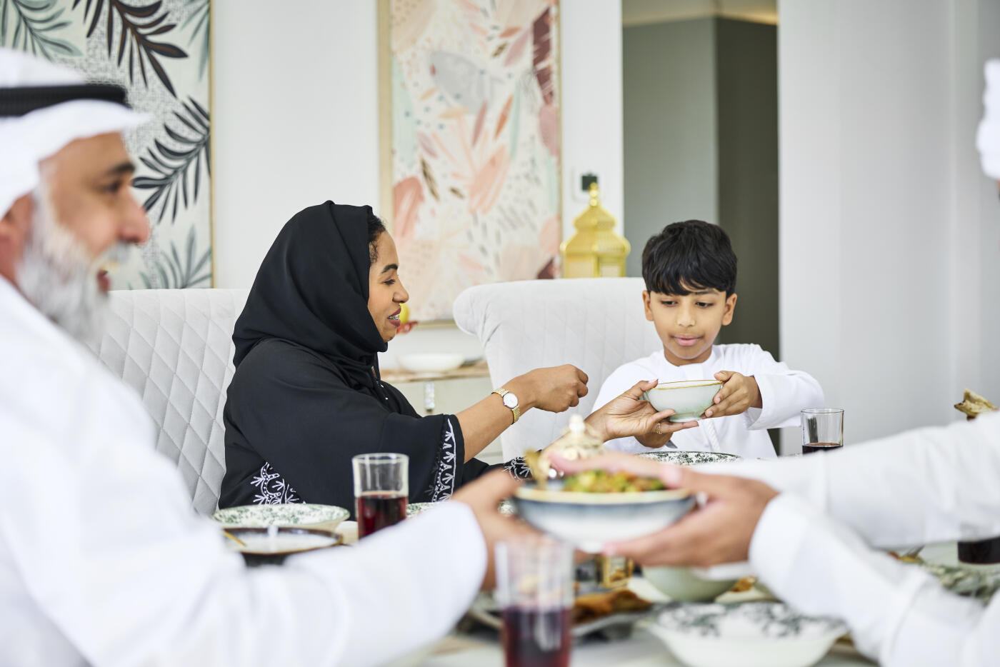 Middle eastern woman passing food bowl to son