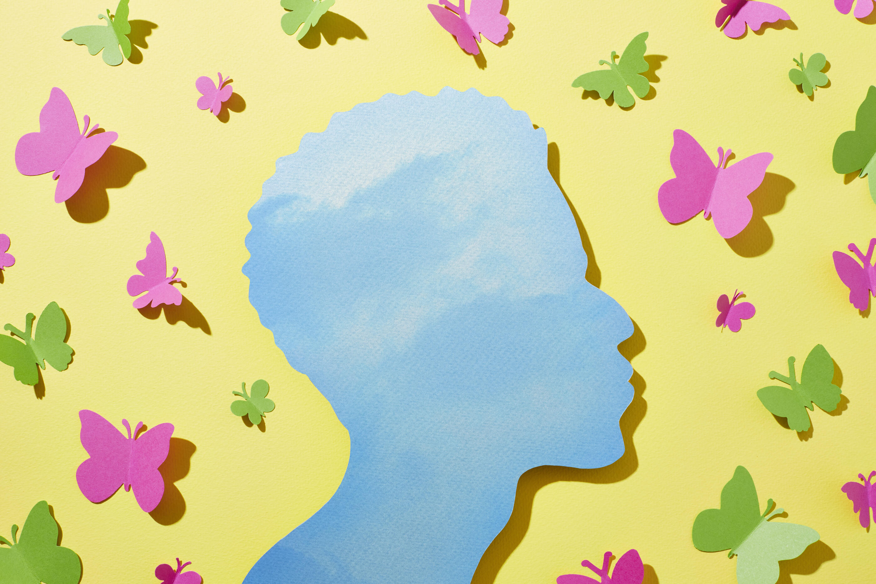 A man surrounded by butterflies with a clear blue sky in his mind