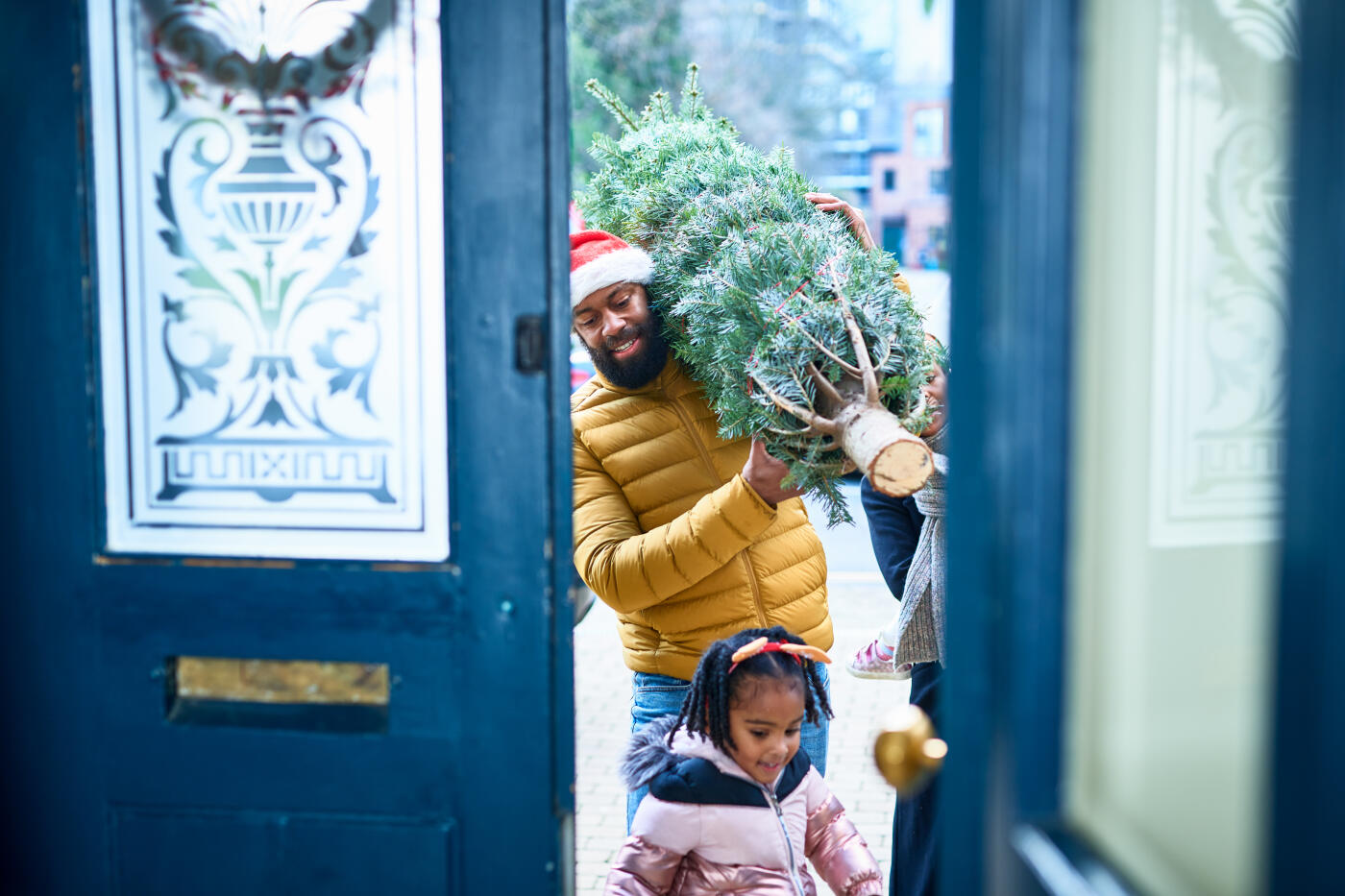 Little girl leading the way with father behind holding Christmas tree, arriving home, family tradition, childhood, excitement, preparing for Christmas