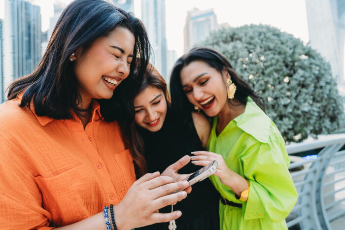 Young women laughing while looking at a smartphone in Dubai