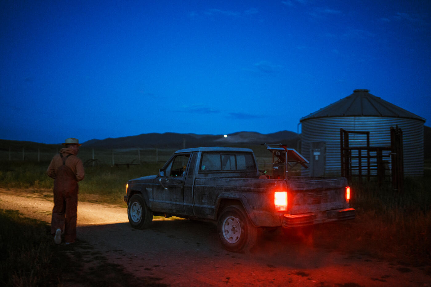 Before sunrise, two ranchers leave their rural Wyoming ranch in a pickup truck to install a solar-powered fence in a nearby agricultural field.