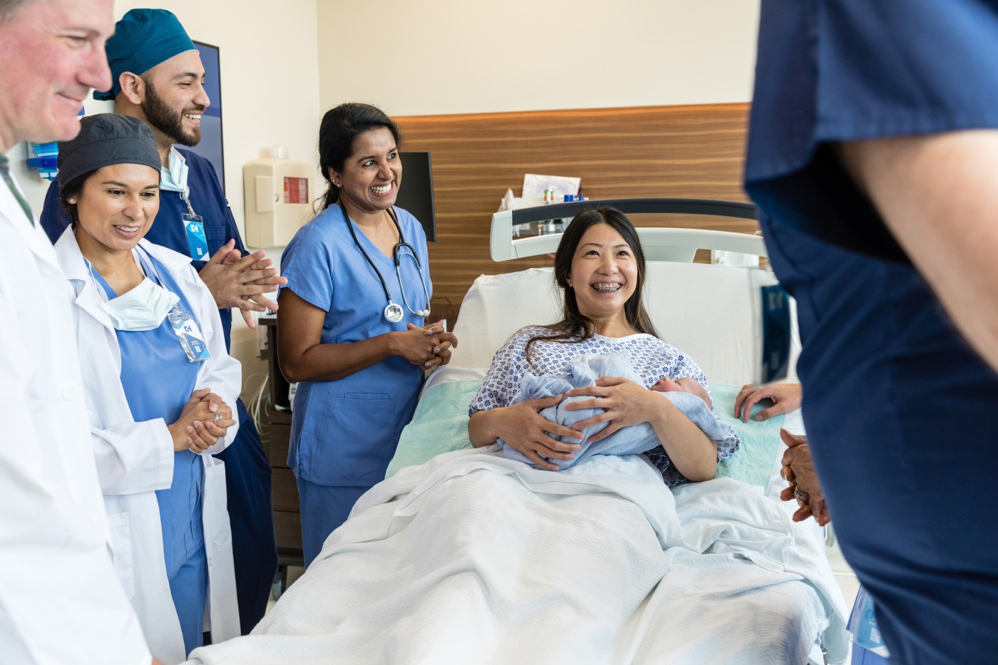 The emergency room medical team gathers around the mid adult new mid adult mom's bed.
