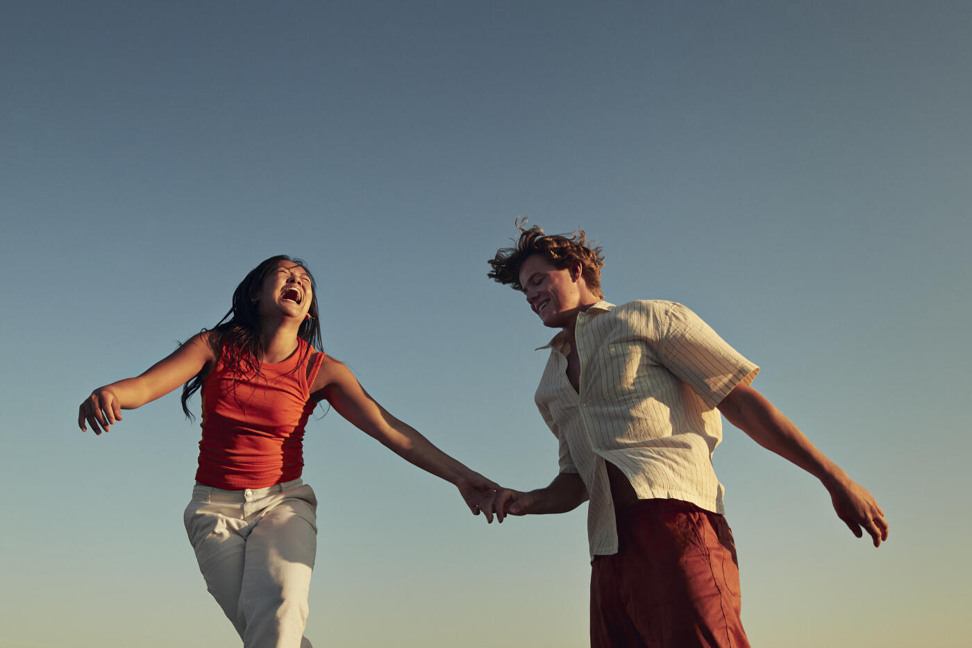 Low angle view of happy friends enjoying against clear blue sky