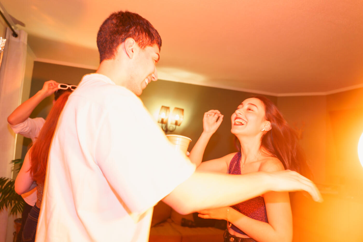 Young adults enjoying a house party, dancing together and laughing