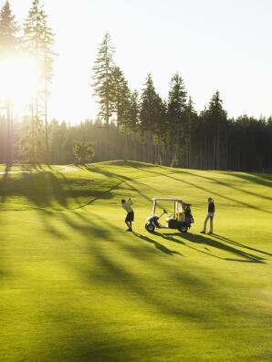 Couple on golf course with golf cart, man swinging golf club