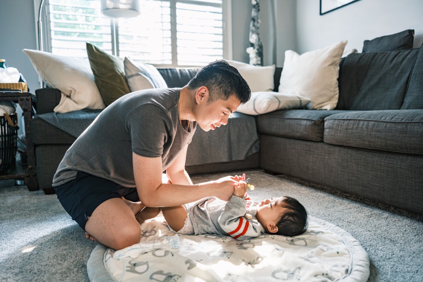 Young Korean Father at Home with toddler son. Dad is changing clothes of the baby. They are dressed in casual clothes. Interior of private home in Toronto, Canada.