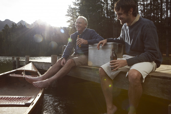 Father and son having a beer on jetty