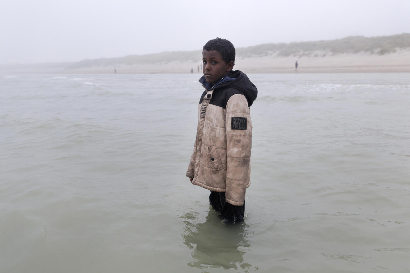GRAVELINES, FRANCE - JULY 02: A boy stands forlorn after failing to board small boat on July 02, 2025 in Gravelines, France. The boat had arrived through the fog, already very full of migrants who had boarded further down the coast, looking to squeeze a few more people in. Last month, it was reported that French officials were planning changes to policies that govern interceptions at sea, allowing police to intercept small boats within 300 metres of the French shoreline, in a bid to curb migrant crossings of the English Channel. The move, which has not been confirmed, would be welcomed by UK authorities, who see it as a step toward stronger border enforcement. (Photo by Dan Kitwood/Getty Images)