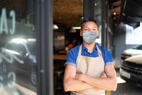 Portrait of owner / waiter at restaurant using protective mask