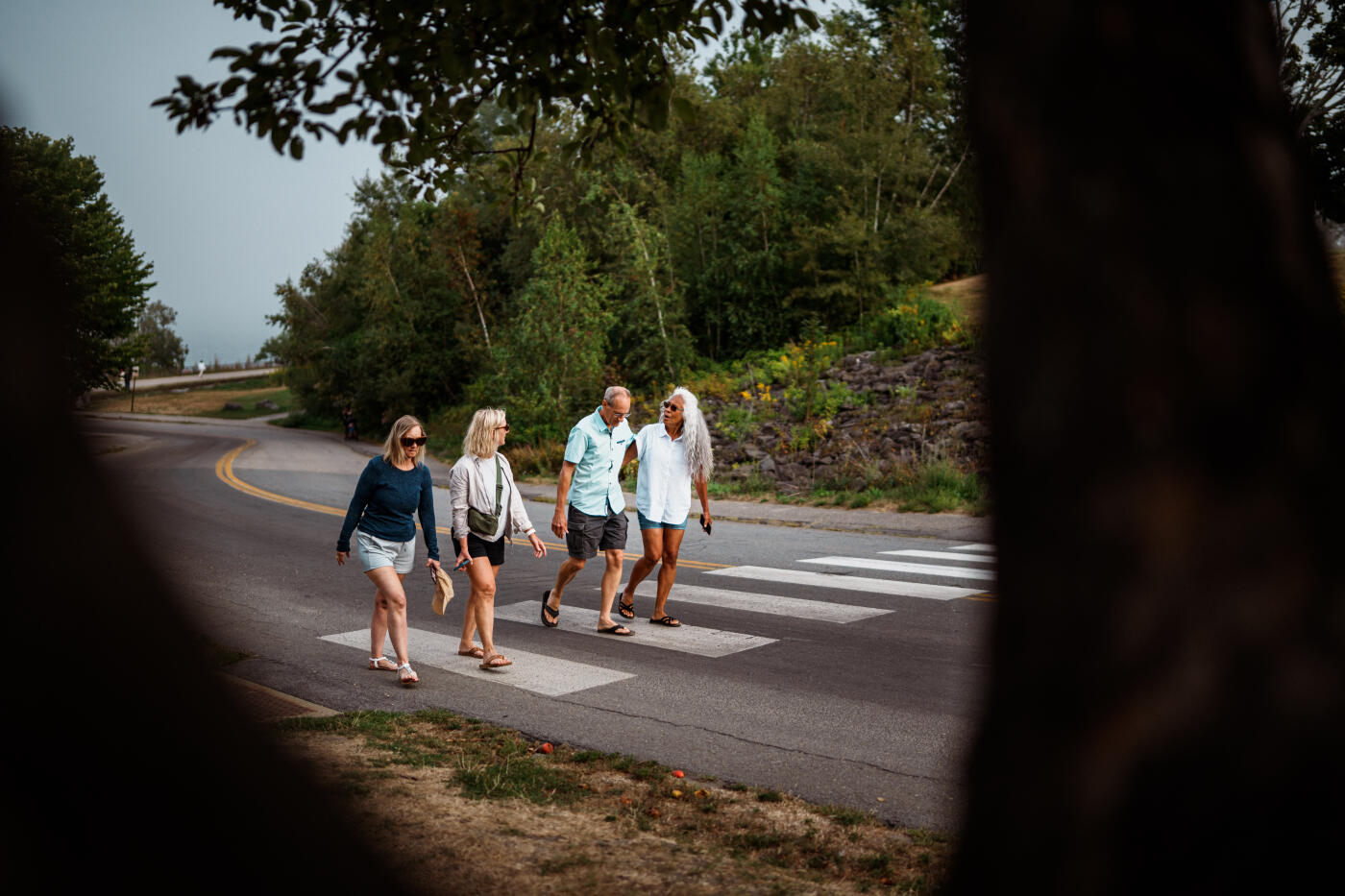 A multiracial group of senior adult friends cheerfully chat as they walk together along a road toward their parked cars after spending a summer afternoon kayaking off the shore in Portland, Maine.