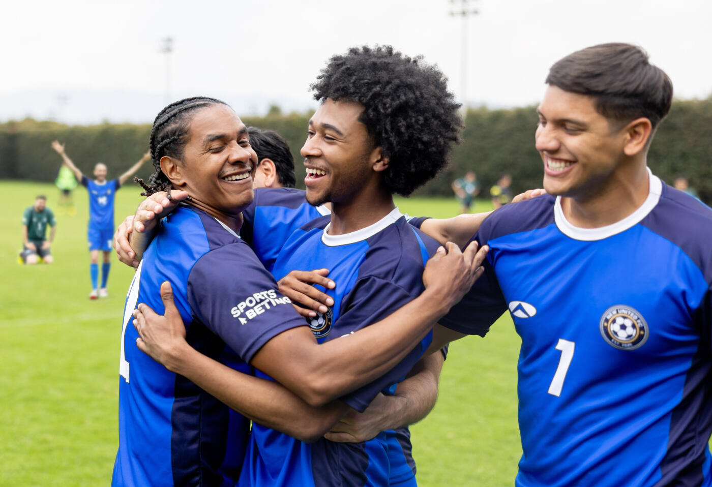 Happy group of Latin American soccer players hugging in the field while celebrating a goal - sport concepts