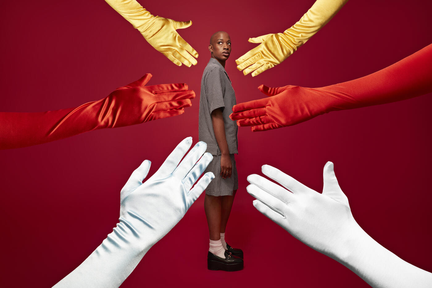 Side view full length of worried non-binary person with ADHD standing amidst hands cut out against red background