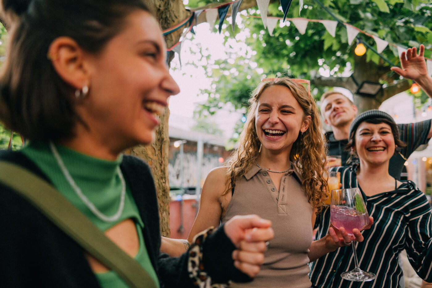 A cheerful gathering of friends celebrating together under bright lights and festive decorations. The scene captures laughter, fun, and colorful moments between close companions enjoying drinks and good times. Part of a series with video
