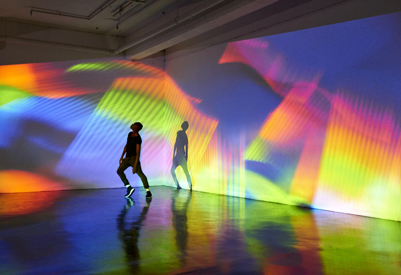 Man dancing in front of large scale abstract image being projected onto the walls behind him