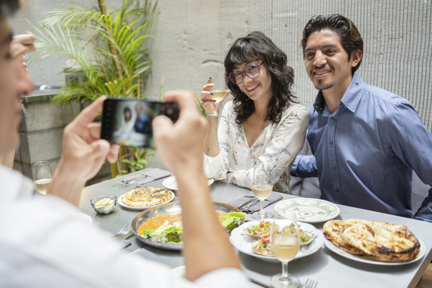 A group of young professionals enjoying a delicious meal with friends in a modern and elegant restaurant while taking photos with their phones.