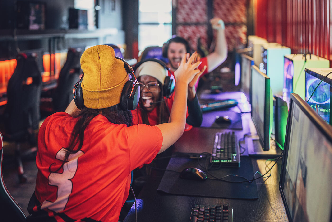 Multiracial group of people, professional cybersport gamers playing video games on esports competition on desktop computers together in gaming club.