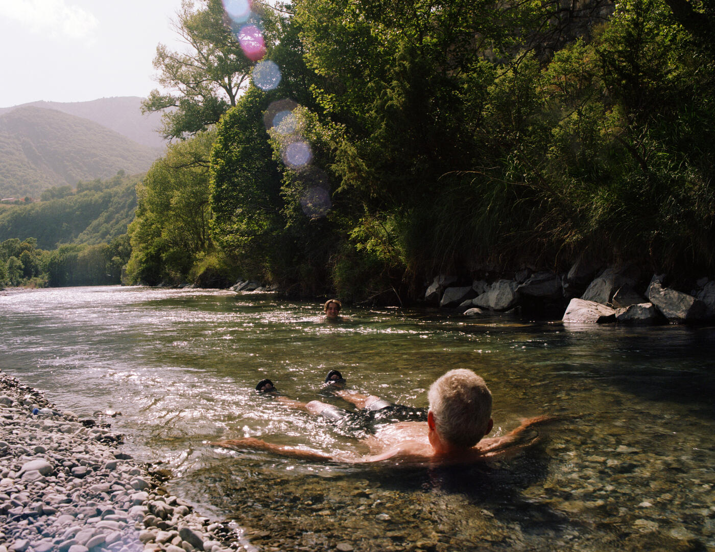 Father and daughter swimming in shallow mountain river. Summer