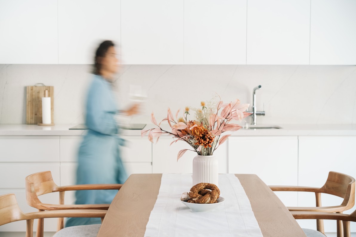 Blurred woman in a wardrobe is walking through the kitchen. Modern minimalistic interior.