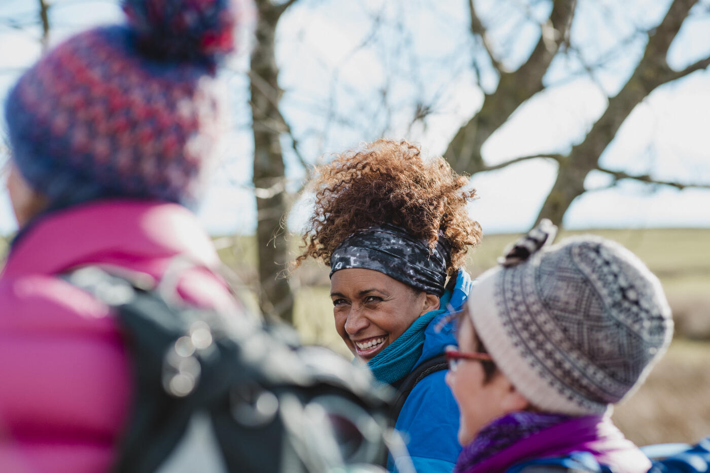 Mature woman is laughing with friends while hiking in the countryside.