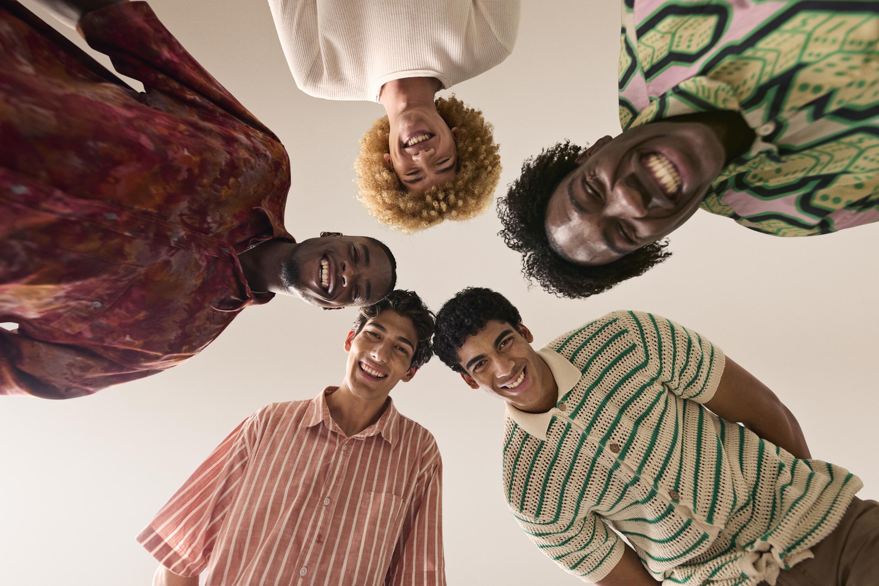 Directly below shot of happy young male friends against beige background