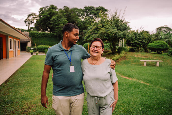 Volunteer walking in garden with elderly woman in nursing home
