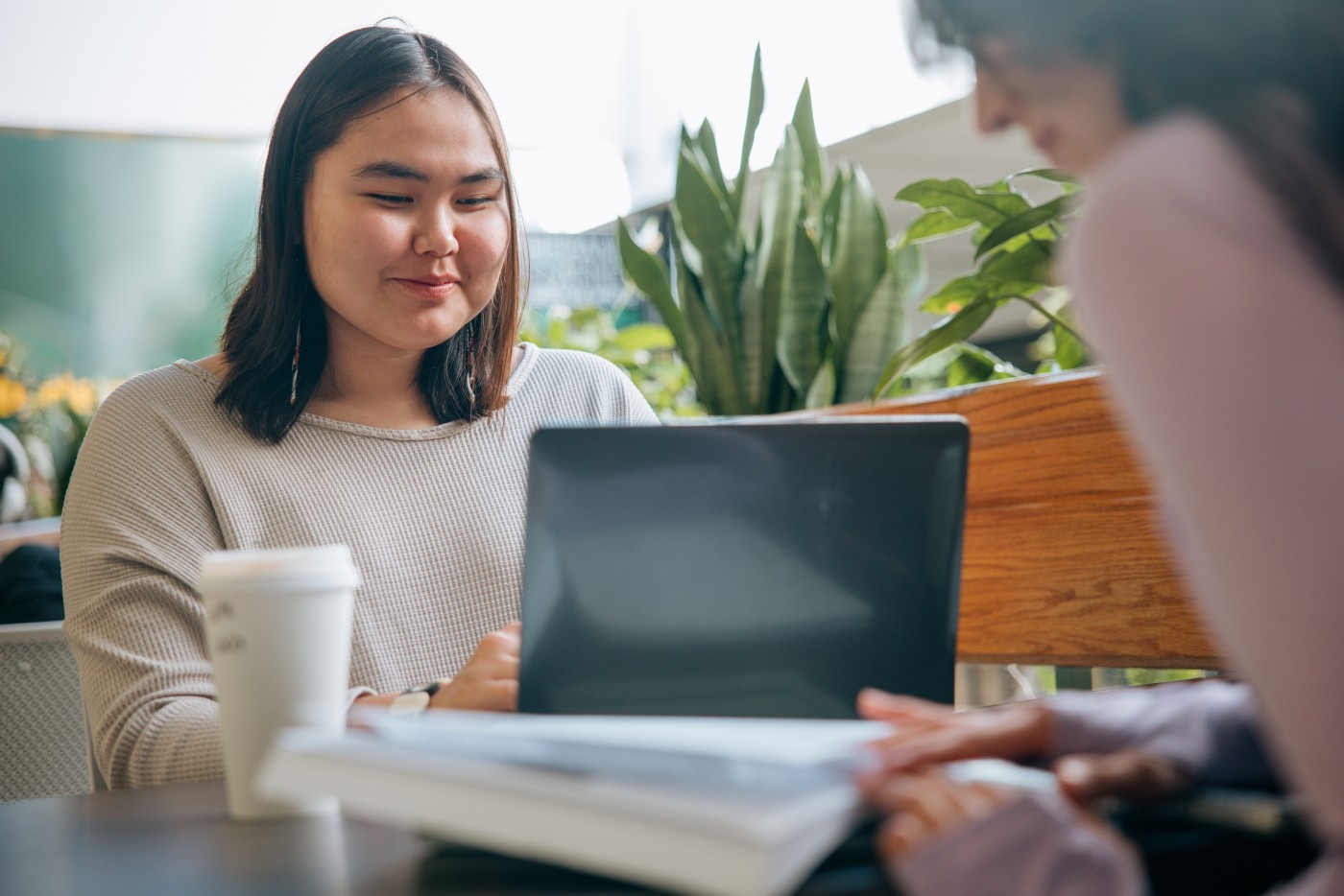 Two Indigenous Alaskan woman at University work, study, and talk at a coffee shop.  Shot in Anchorage, Alaska, USA.