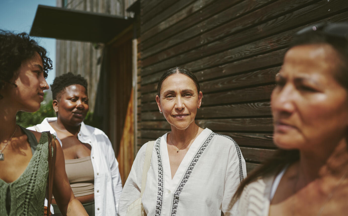 Smiling mature woman standing outside after a yoga class with friends on a patio at a wellness retreat in the summertime