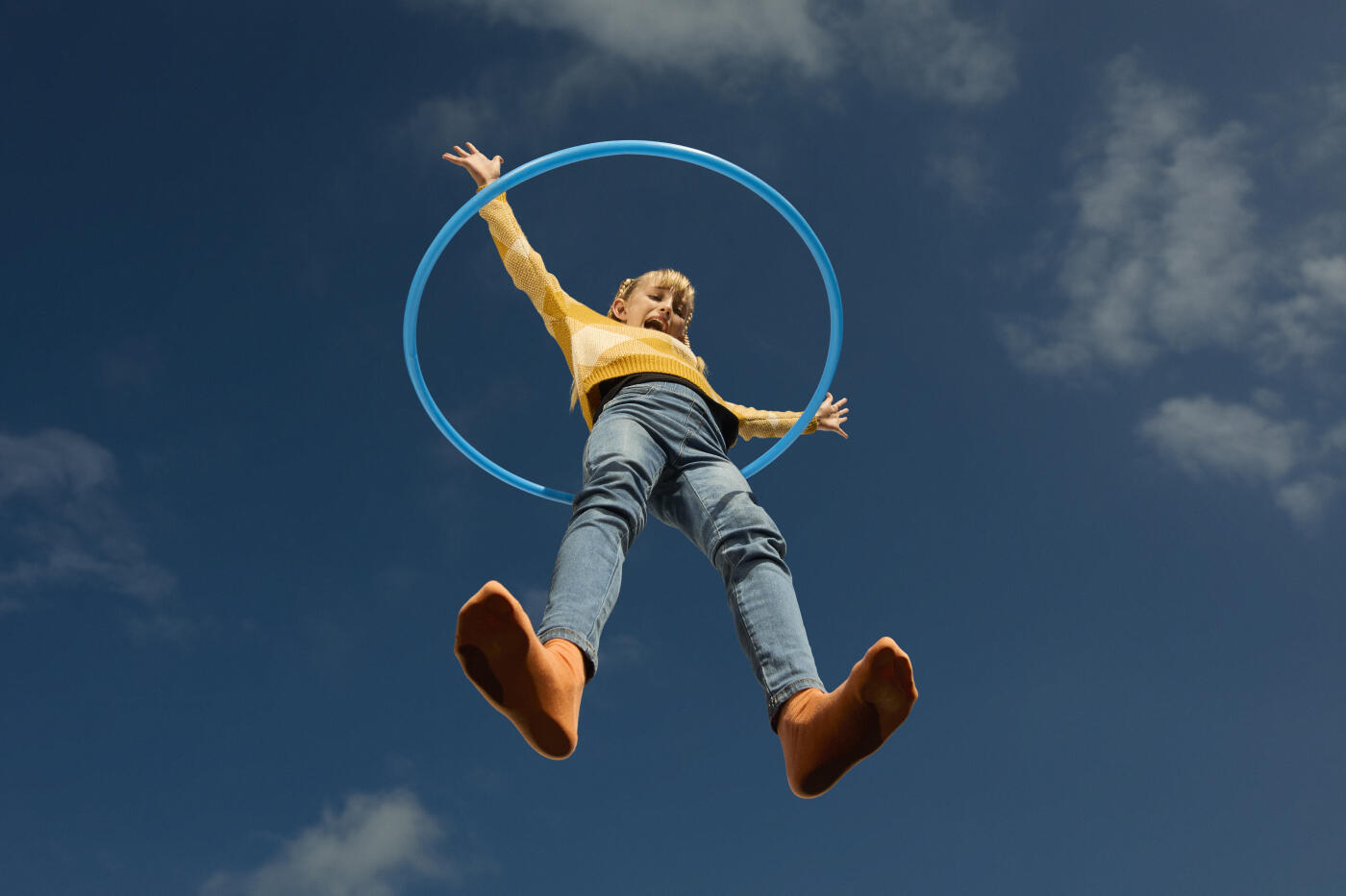 Directly below shot of girl spinning hula hoop on glass surface