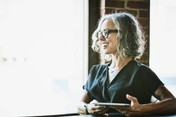 Smiling businesswoman with digital tablet listening during meeting in office