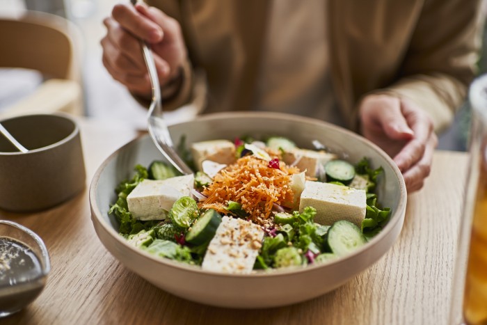 Asian woman enjoying lunch at a vegan cafe.
