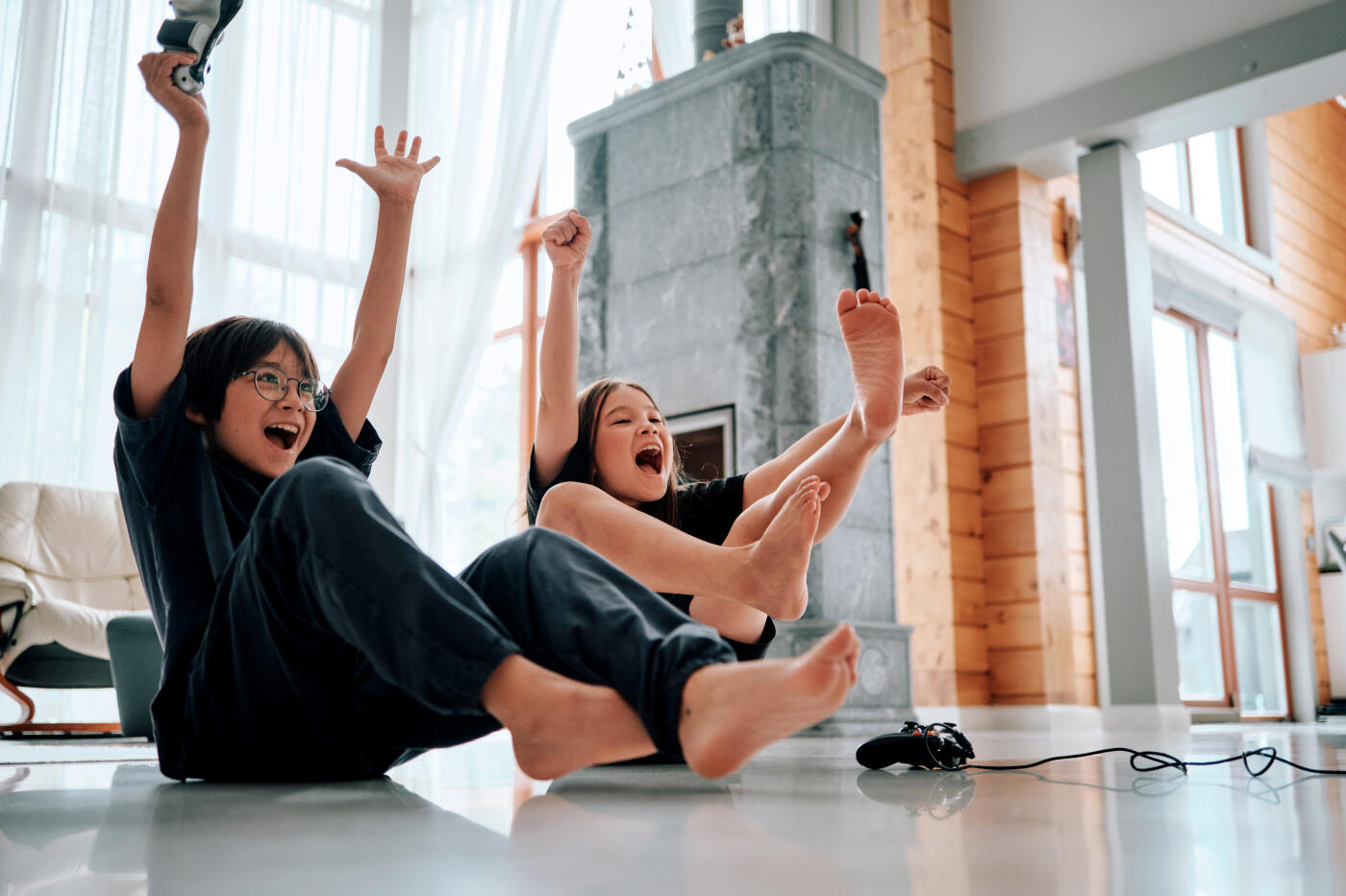 Brother and sister are playing video games on a console while sitting on the floor.