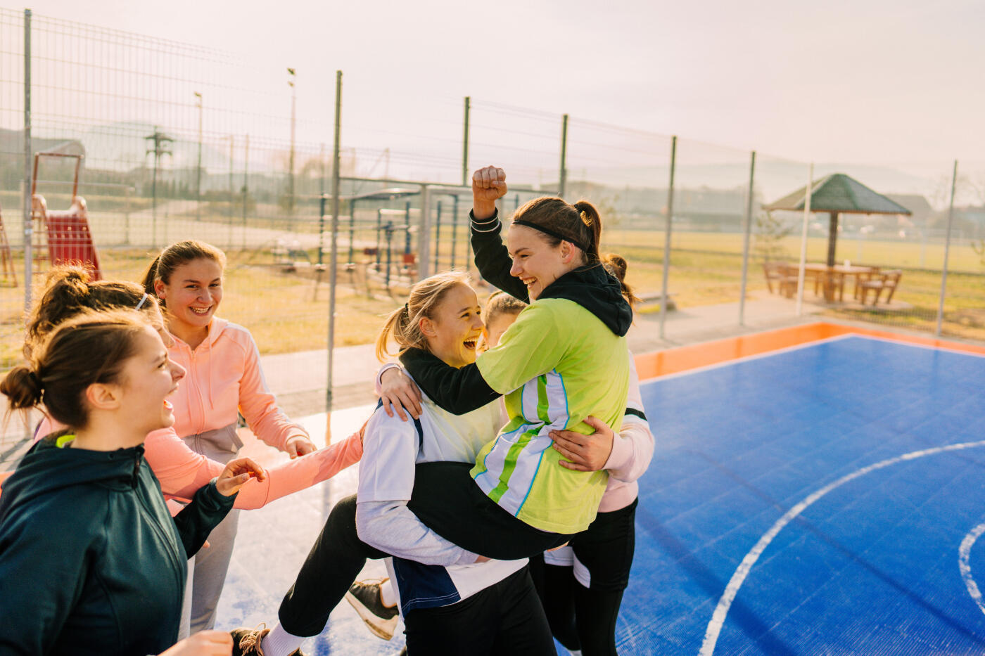 Photo of smiling teenage girls on a basketball court celebrating after the great match