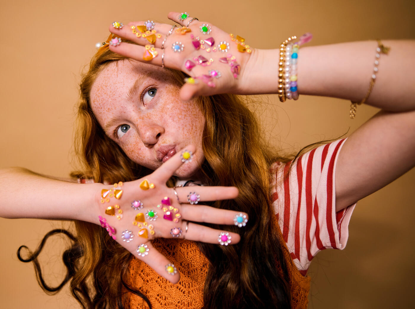 Young girl with red hair and freckles playing, covering hands with decorative flower stickers