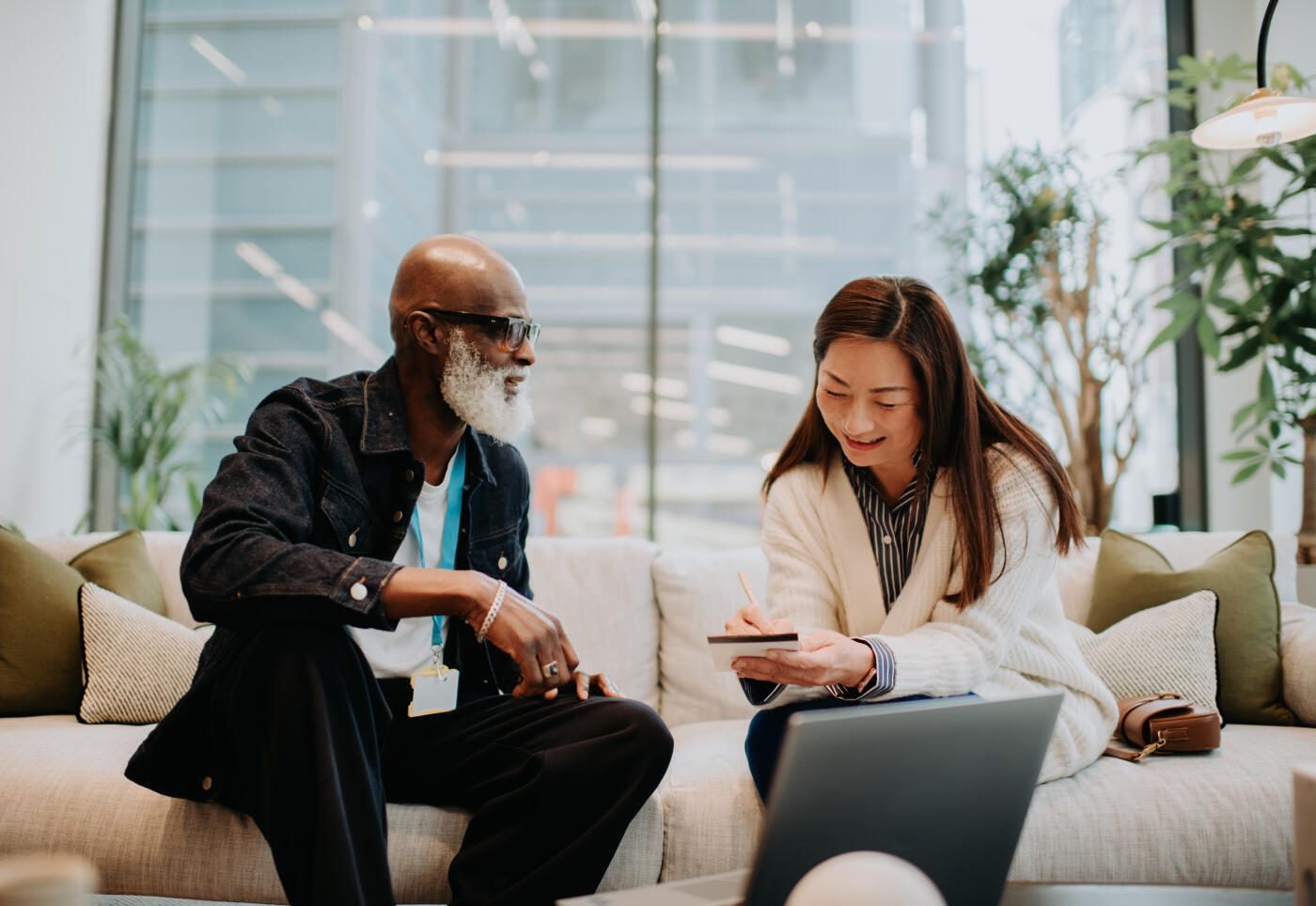 A man and a woman have a casual meeting from a sofa in a commercial office setting.