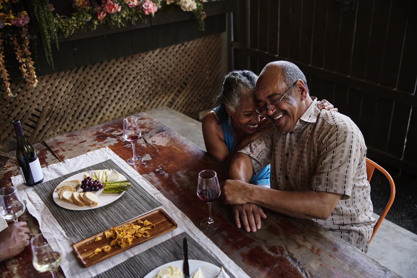 High-angle view of a happy, mature woman embracing a man while seated at a table in a restaurant.