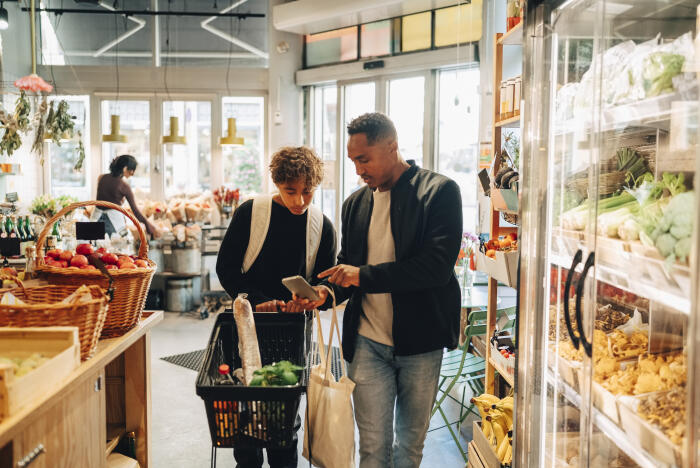 Father and son looking at shopping list in smart phone while buying groceries in supermarket