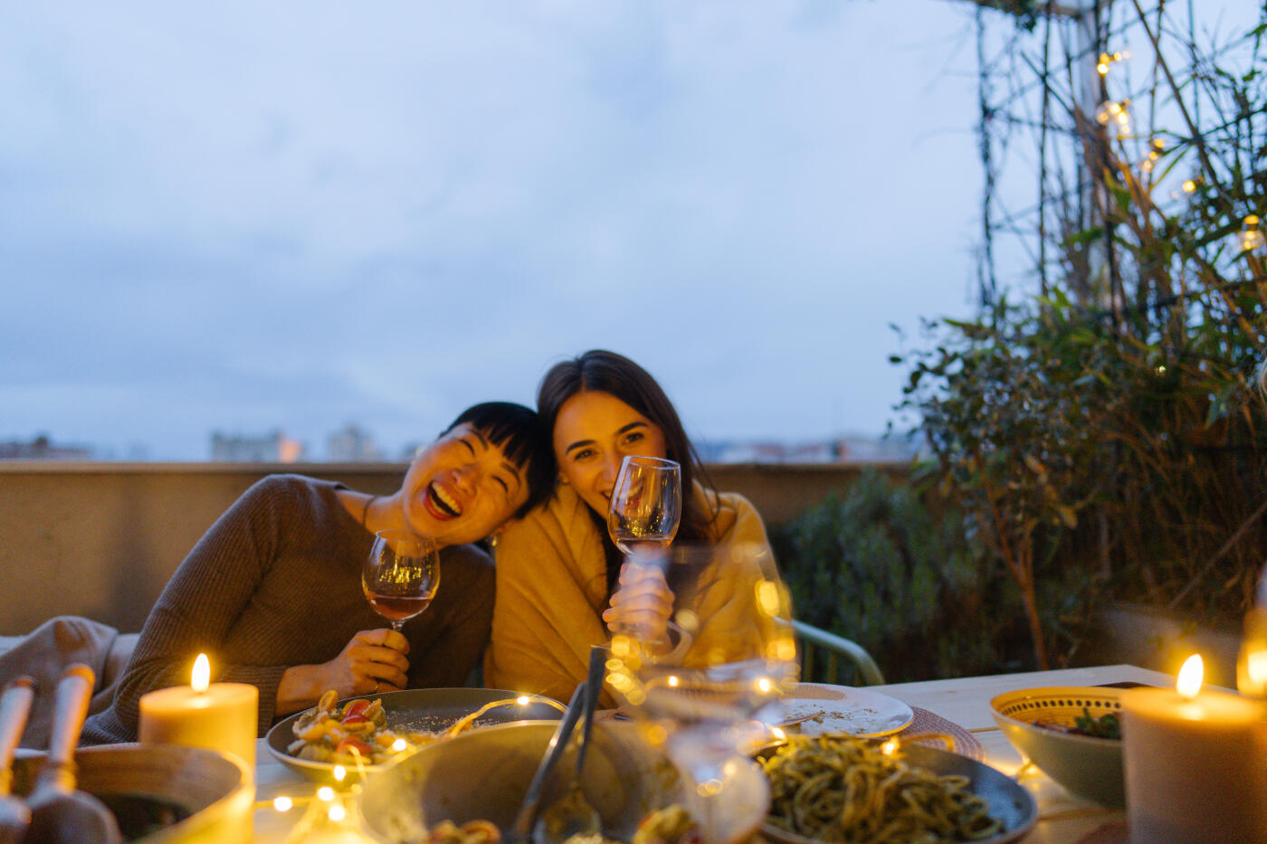 Photo of a couple of female friends, having a meal and drinking wine on an open terrace and enjoying their time together.