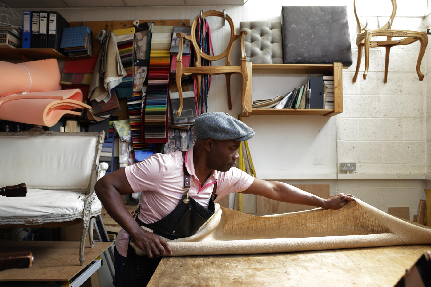 An upholsterer at work in his studio workshop measuring out material - small business