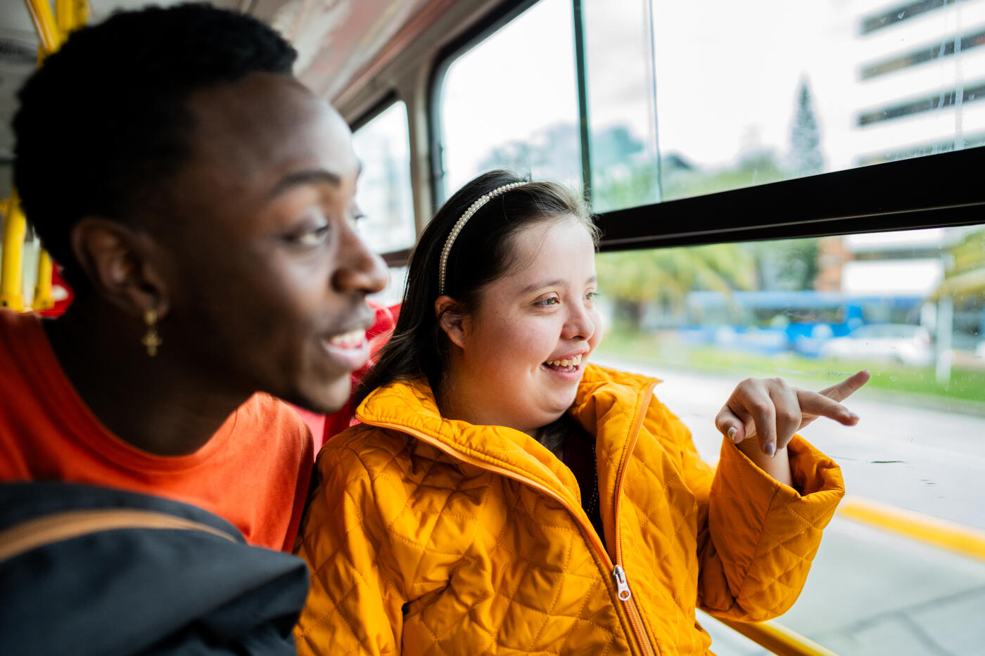 Young woman with down syndrome and friend looking through window on the bus