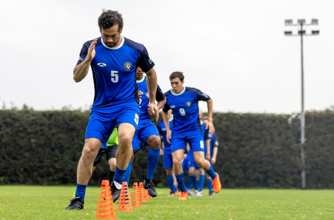 Group of soccer players doing warm up exercises during practice - sports training concepts