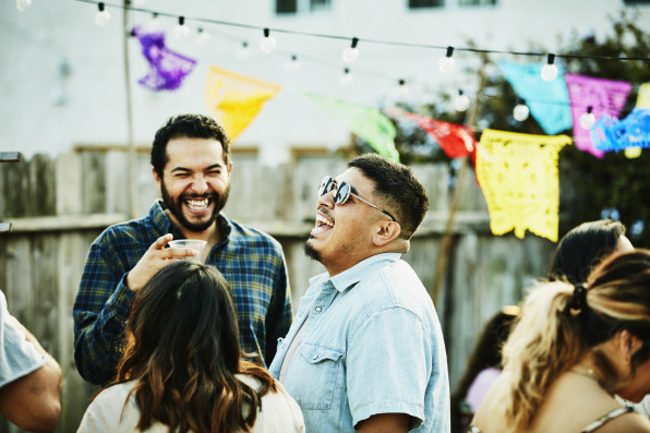Laughing friends hanging out during backyard barbecue on summer evening