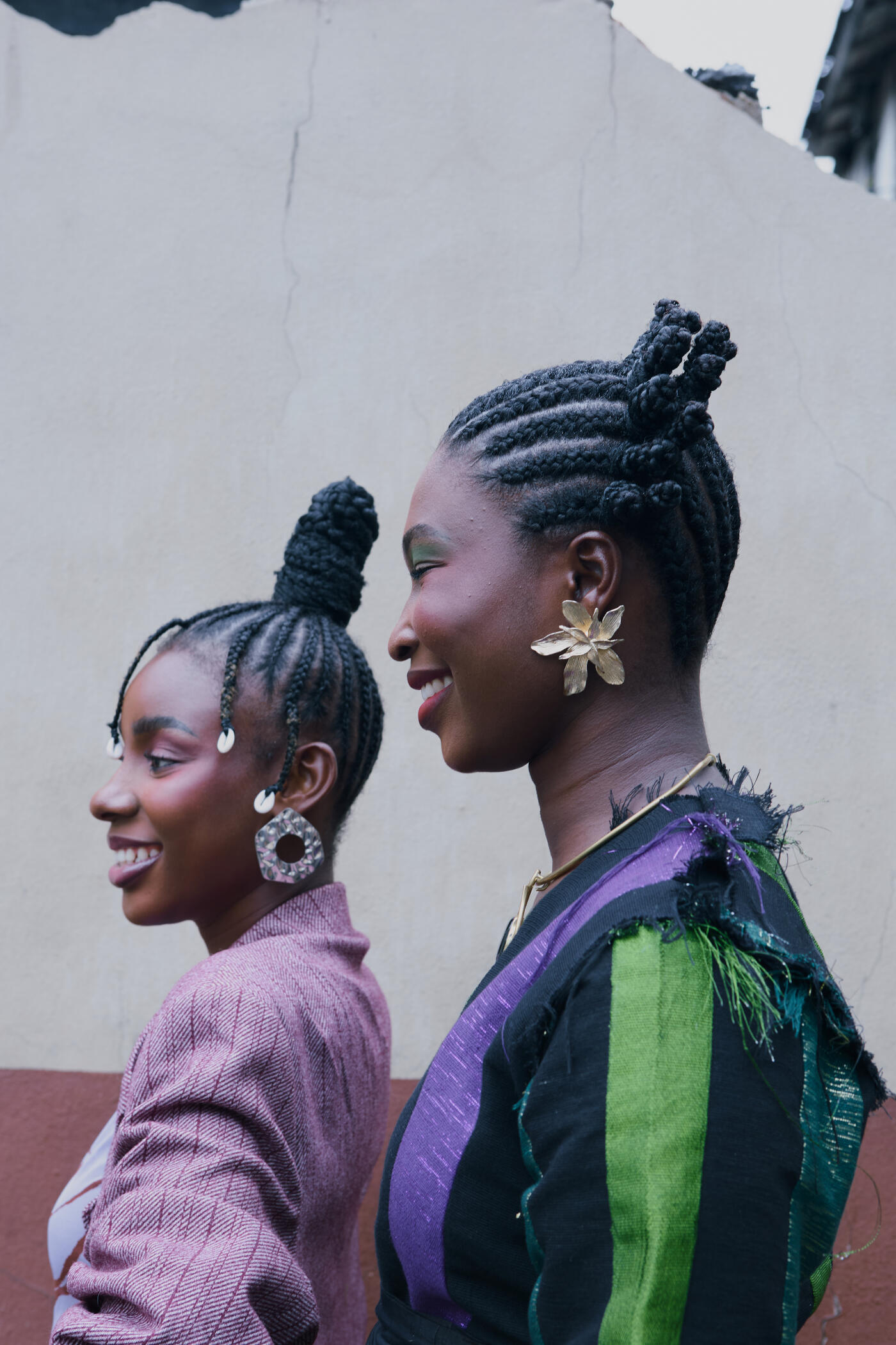 Two young Yoruba women posing for a photo outside in Lagos Island, Nigeria. They both wear traditional Yoruba braided hairstyles.