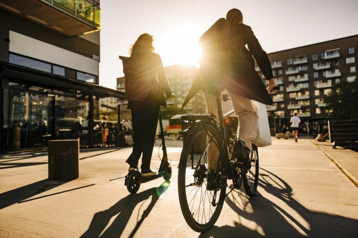 Business people commuting sustainably on promenade at sunset