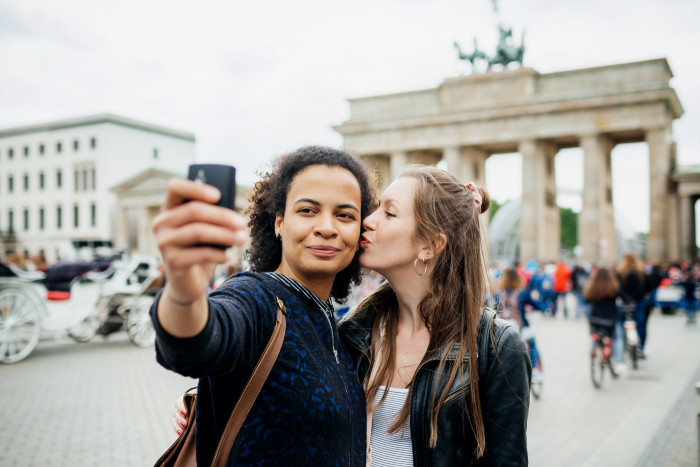 During a trip together a young couple stop for a moment to take a selfie at a local historical site.