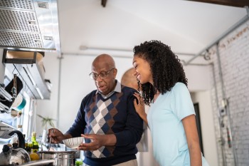 Grandfather serving a soup bowl to granddaughter at home