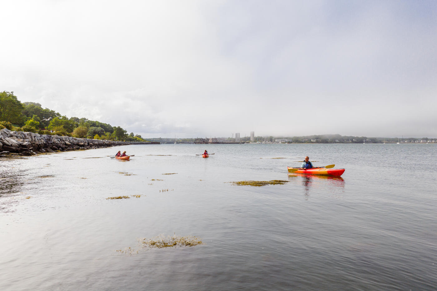 A small group of senior adult friends kayak in Casco Bay off the shore of Portland, Maine on a summer afternoon.