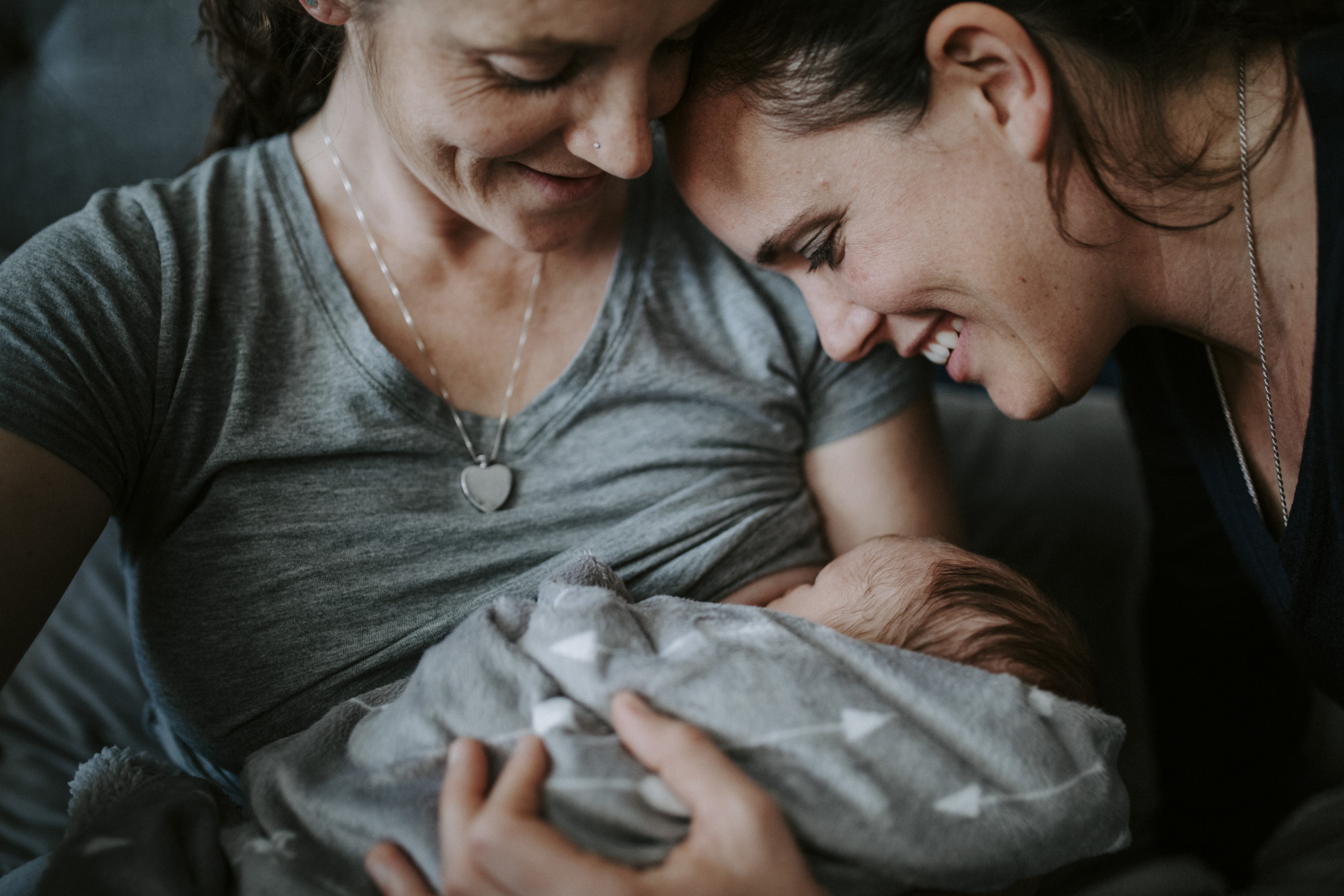 Close-up of lesbian mothers with newborn son on bed at home