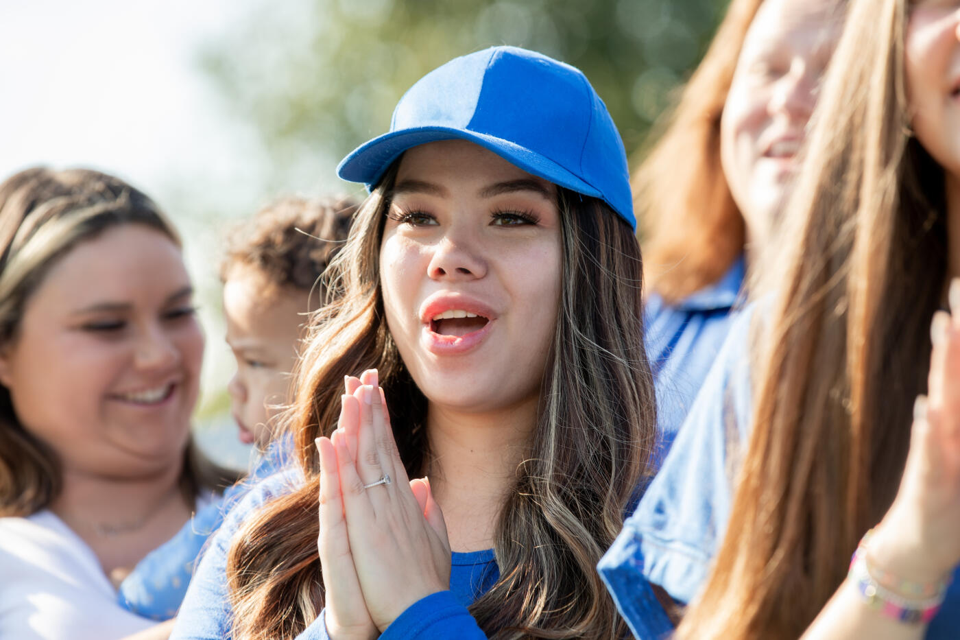Woman cheers on her favorite college football team with other fans in stadium bleachers