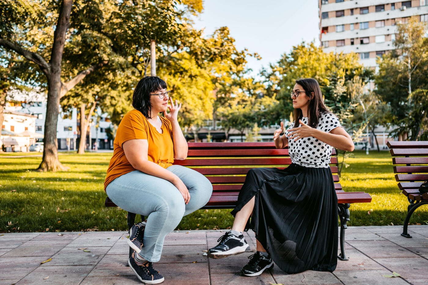 Two deaf and hard hearing women speak in sign language outdoors.