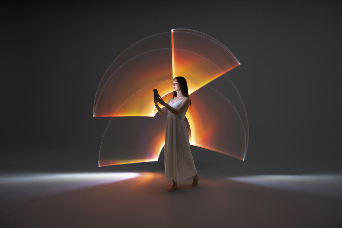 Young woman using a smart phone in front of orange light trails.